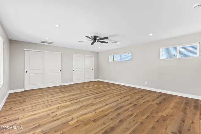 a view of empty room with wooden floor and ceiling fan