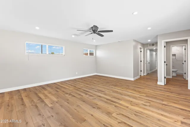 a view of empty room with wooden floor and ceiling fan