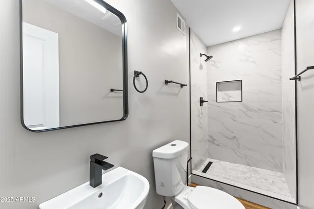 a bathroom with a sink a toilet and shower