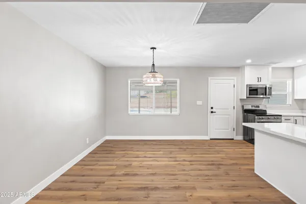 a big room with chandelier fan and wooden floor