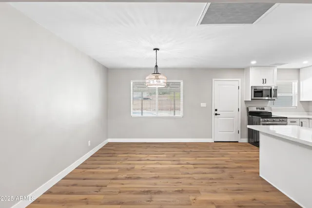 a big room with chandelier fan and wooden floor