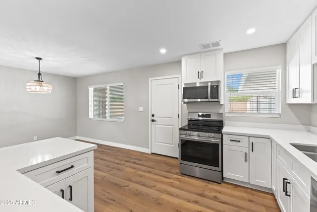 a kitchen with granite countertop a stove cabinets and wooden floor