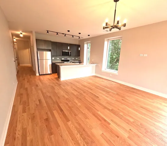 a view of a kitchen with kitchen island a sink wooden floor and a large window
