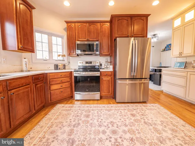 a kitchen with stainless steel appliances granite countertop wooden cabinets granite counter tops and a window