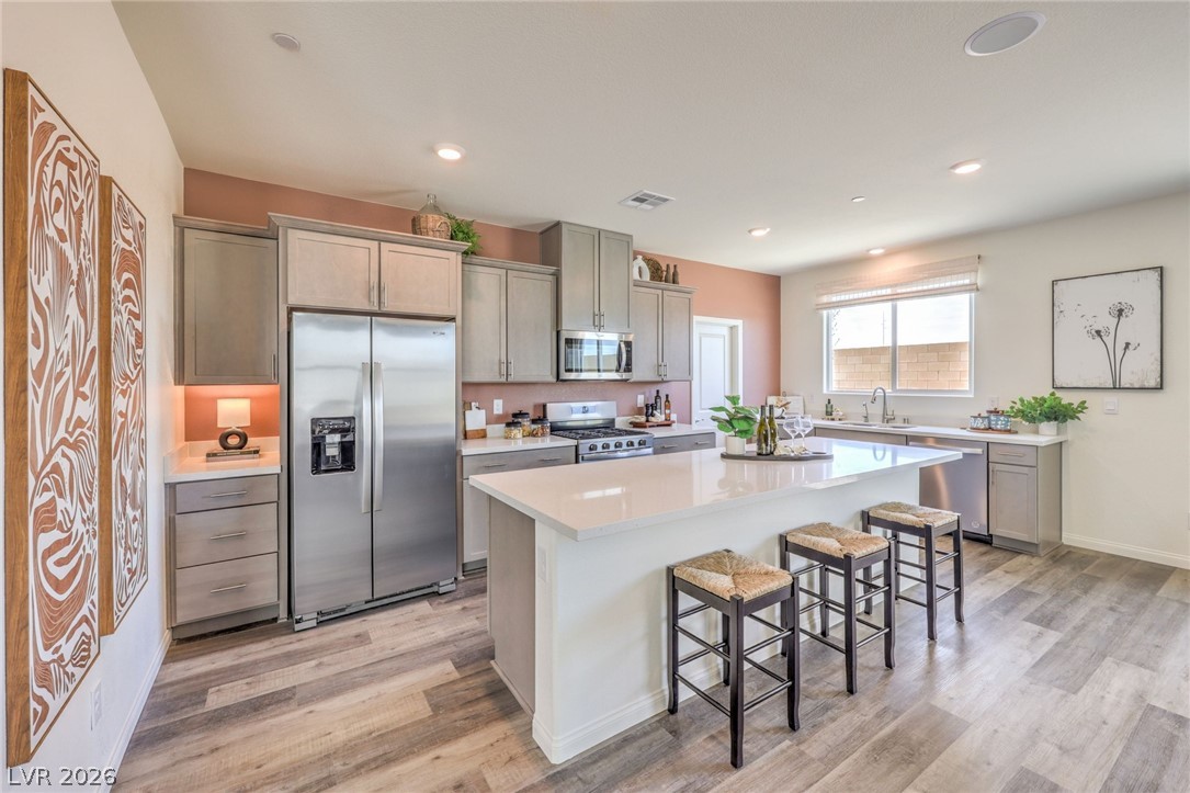 1013 Copper Robin Street Henderson, NV 89011 - Photo 14 of 43 Kitchen with appliances with stainless steel finishes, light wood-style. Photo is representational only; actual home finishes may vary flooring, a breakfast bar, light countertops, and recessed lighting