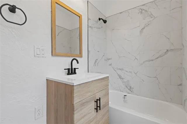 a bathroom with a sink vanity mirror and a bathtub