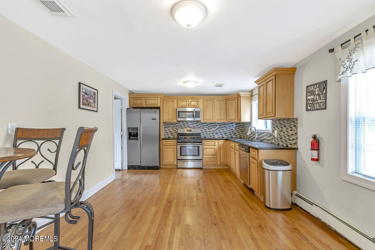 164 Jackson Street Matawan, NJ 07747 - Photo 11 of 26 a large kitchen with stainless steel appliances granite countertop a large stove a sink dishwasher and cabinets with wooden floor