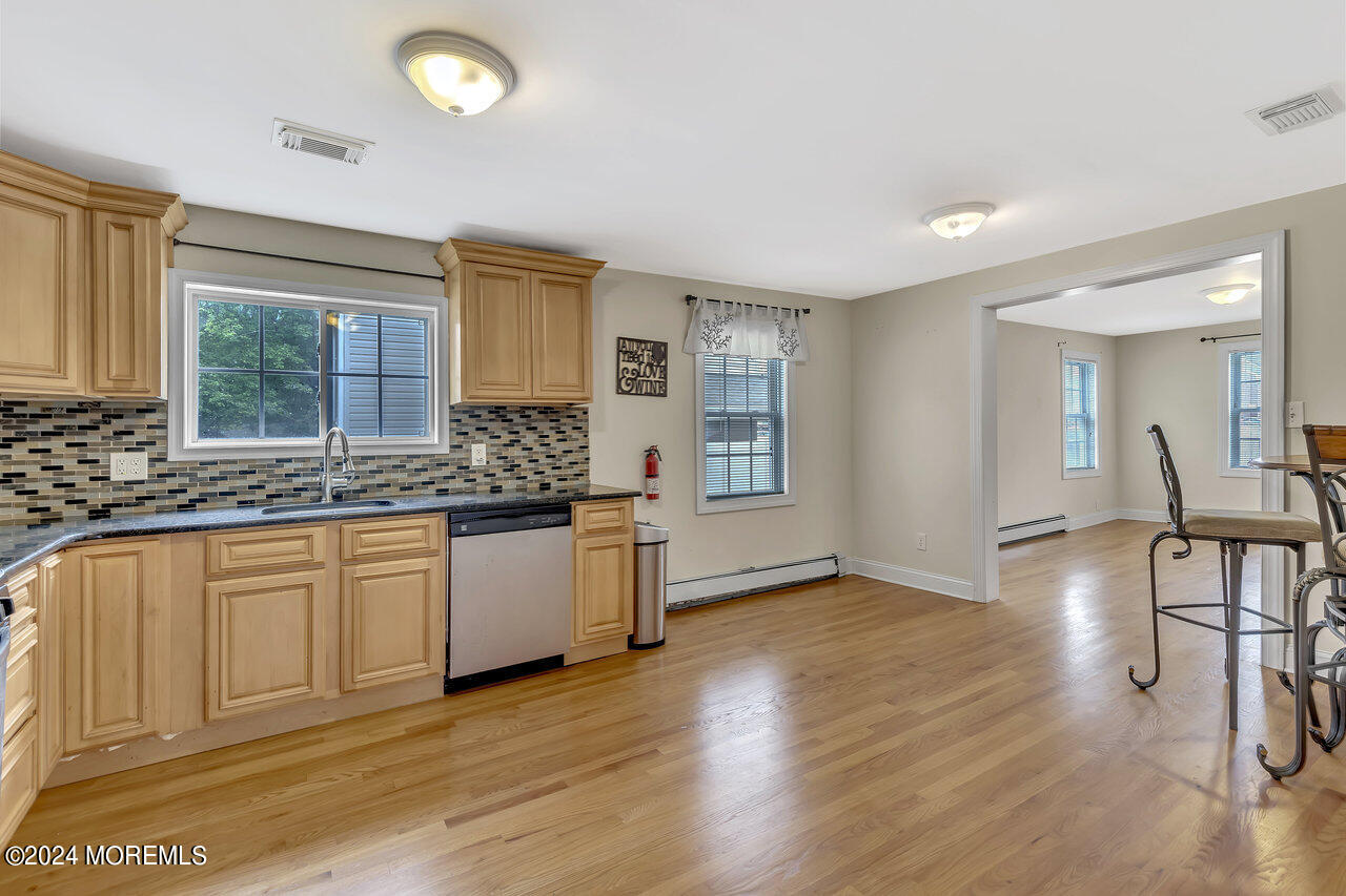 164 Jackson Street Matawan, NJ 07747 - Photo 13 of 26 a kitchen with granite countertop a stove a sink and white cabinets with wooden floor