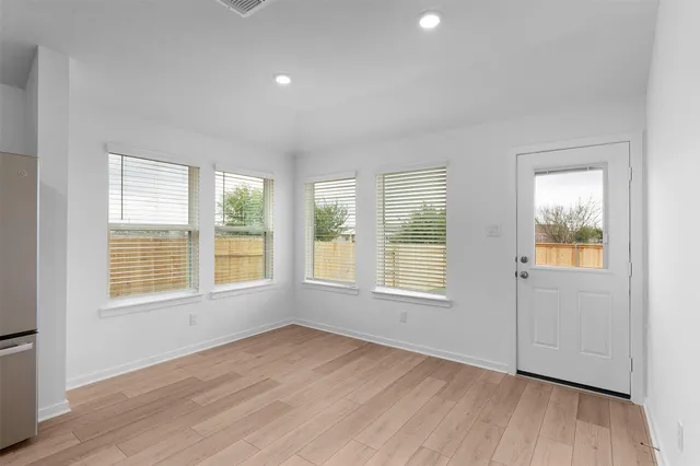 an empty room with wooden floor and windows