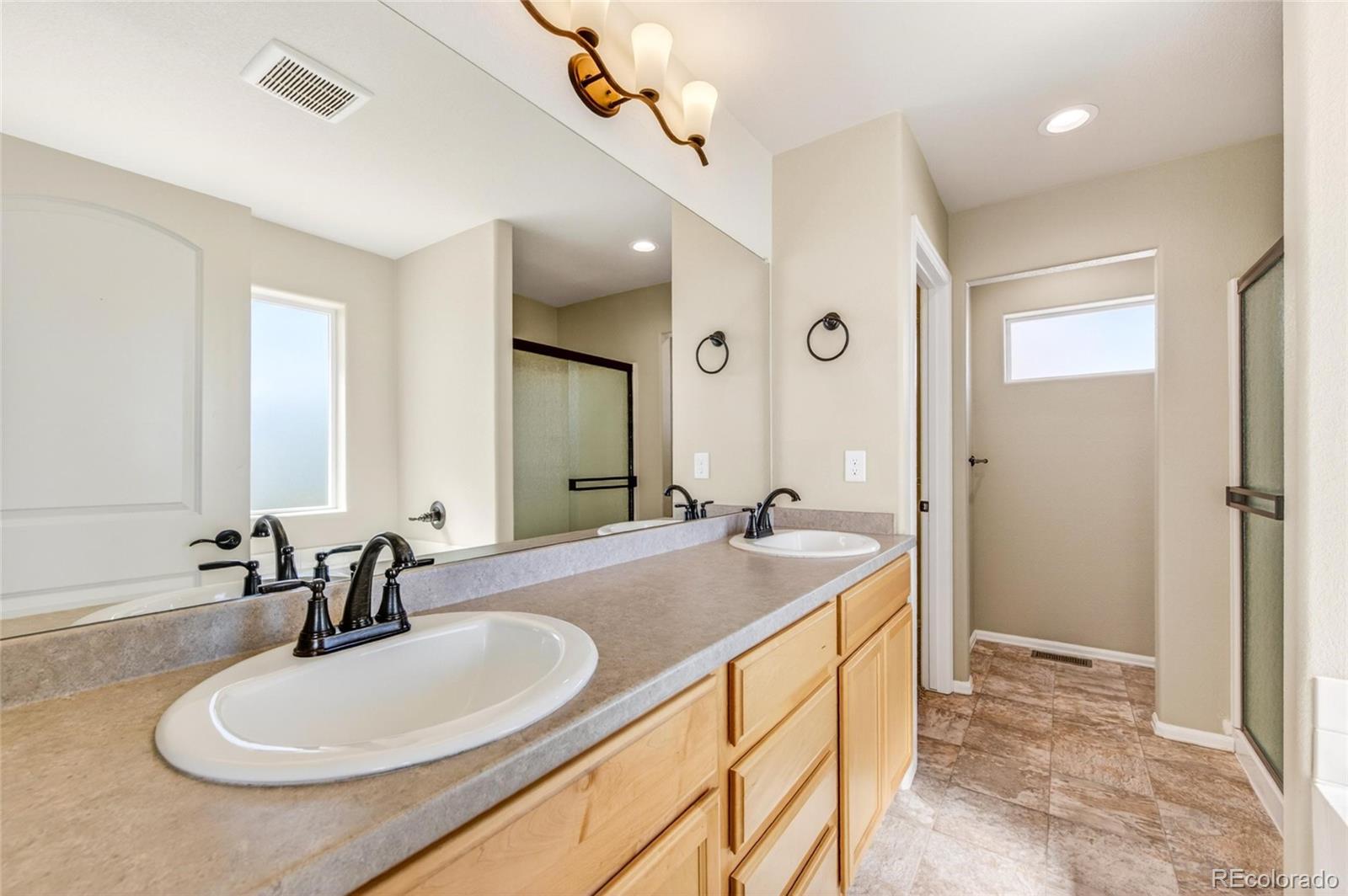 10436 17th Street Greeley, CO 80634 - Photo 11 of 18 a en suite bathroom with a double vanity sink a mirror and a bathtub
