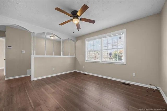 an empty room with wooden floor and windows