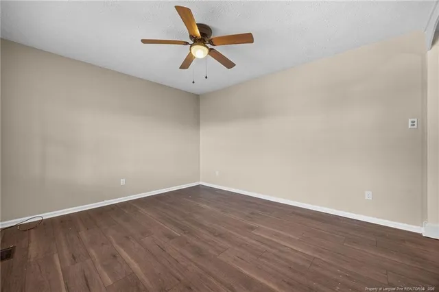 an empty room with wooden floor and a ceiling fan