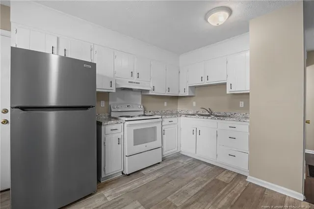 a kitchen with stainless steel appliances granite countertop a refrigerator sink and white cabinets