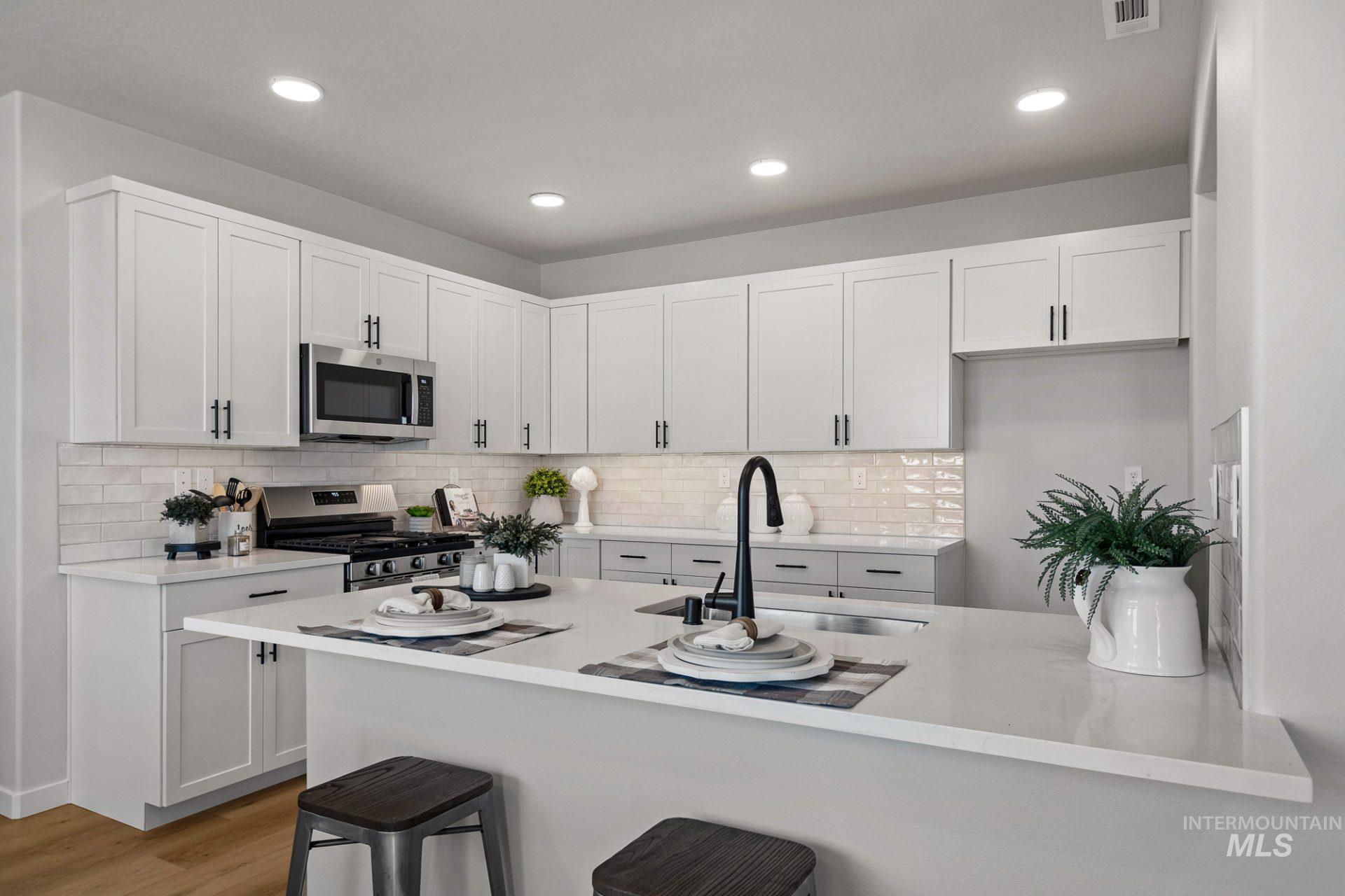 802 Coral Road Kimberly, ID 83341 - Photo 2 of 29 Kitchen with a kitchen breakfast bar, white cabinets, stainless steel appliances, backsplash, and recessed lighting