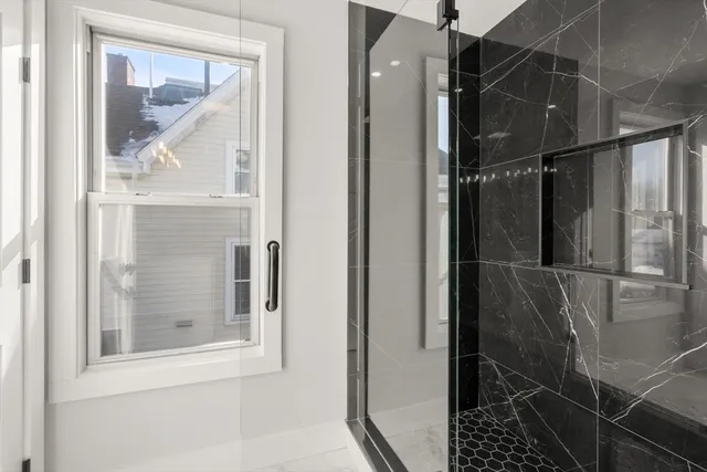 a bathroom with a glass shower door and a window