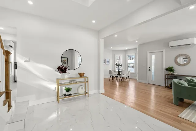 a view of a livingroom with furniture a fireplace wooden floor and windows