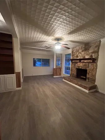 an empty room with wooden floor fireplace and windows