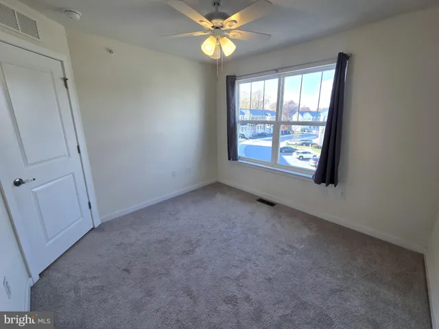 an empty room with windows and fan