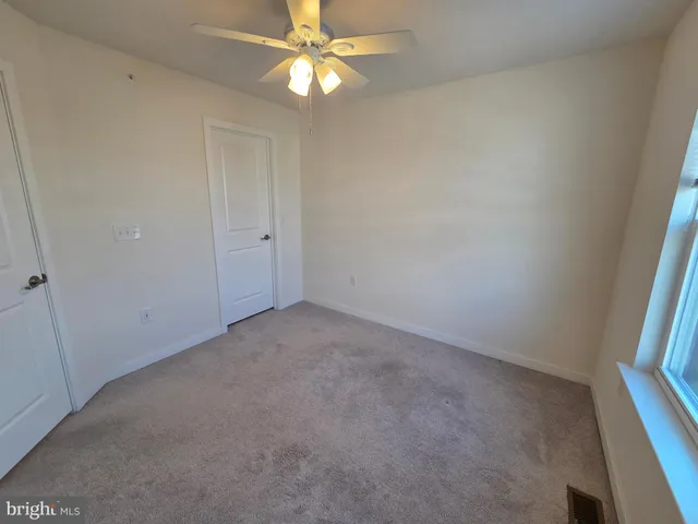 an empty room with a window and a fan