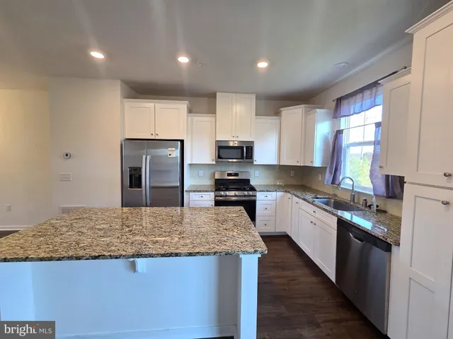 a large kitchen with granite countertop a large counter top stainless steel appliances and cabinets