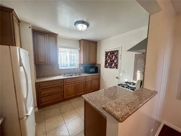 a kitchen with a granite countertop sink and refrigerator