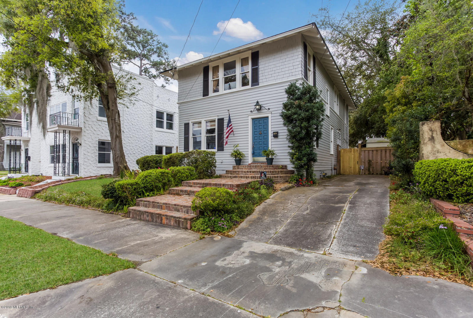 a front view of a house with a yard and potted plants