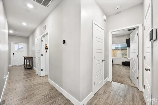 a view of a hallway with wooden floor and a bathroom