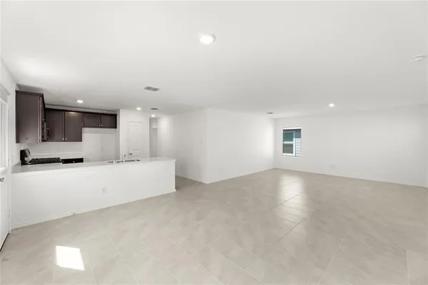 an empty room with kitchen and windows