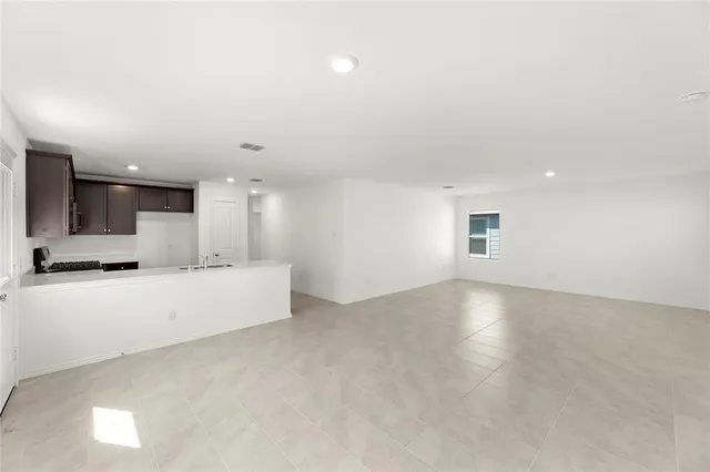 an empty room with kitchen and windows