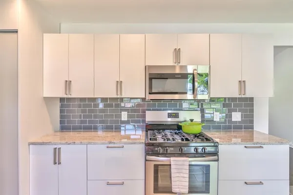 an empty room with wooden floor chandelier fan and windows