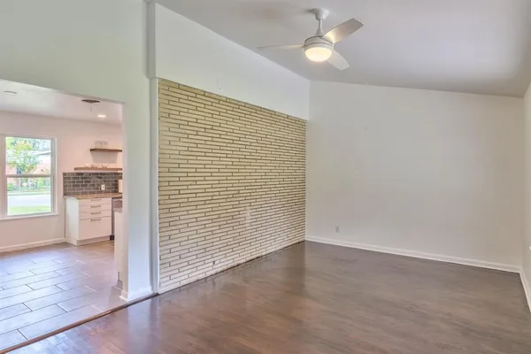 an empty room with wooden floor fan and windows