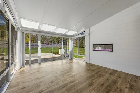 a view of empty room with wooden floor and floor to ceiling window