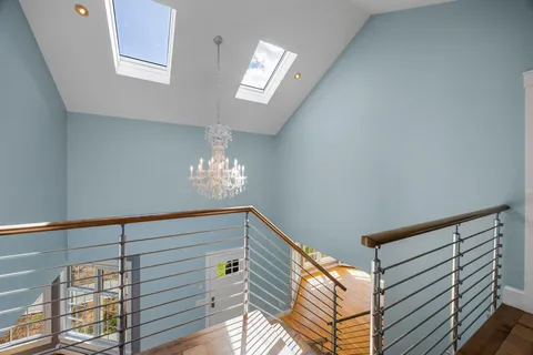 a view of a hallway with wooden floor and chandelier