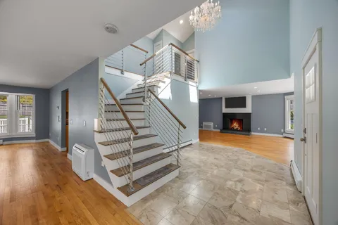 a view of an empty room with wooden floor fire place and windows