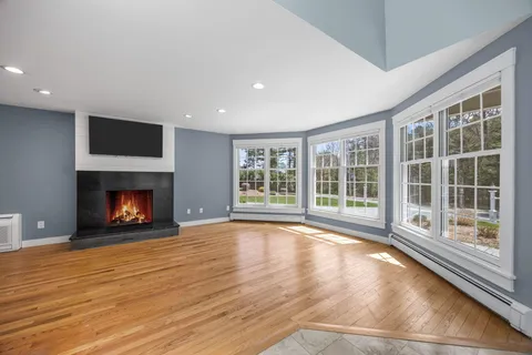a view of empty room with wooden floor and fireplace