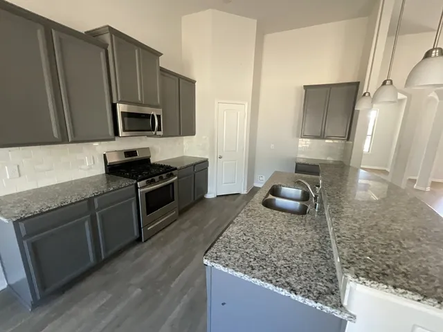 a kitchen with stainless steel appliances granite countertop a sink stove and refrigerator
