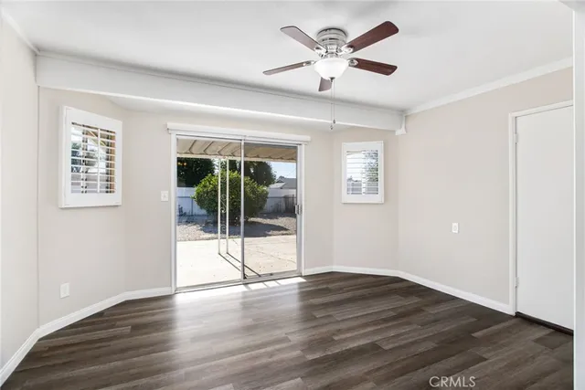 a view of an empty room with wooden floor and a ceiling fan