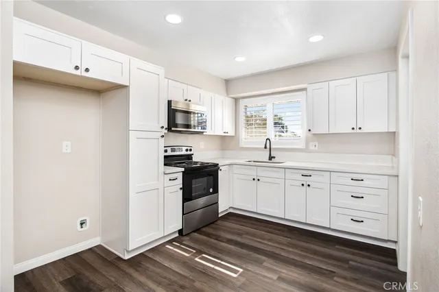 a kitchen with cabinets stainless steel appliances a sink and a window