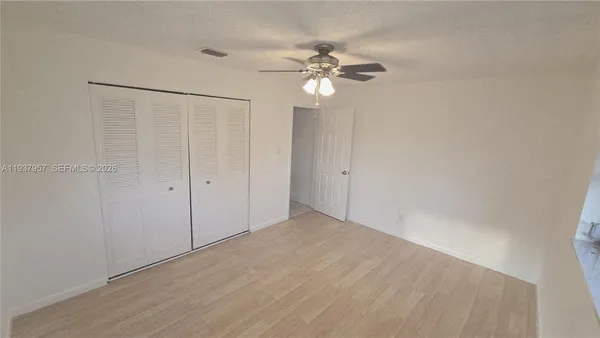 a view of an empty room and chandelier fan