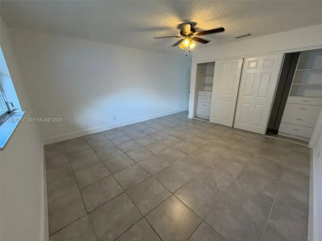 an empty room with closet and chandelier fan