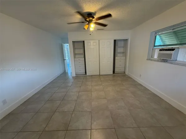 a view of an empty room with a ceiling fan and window