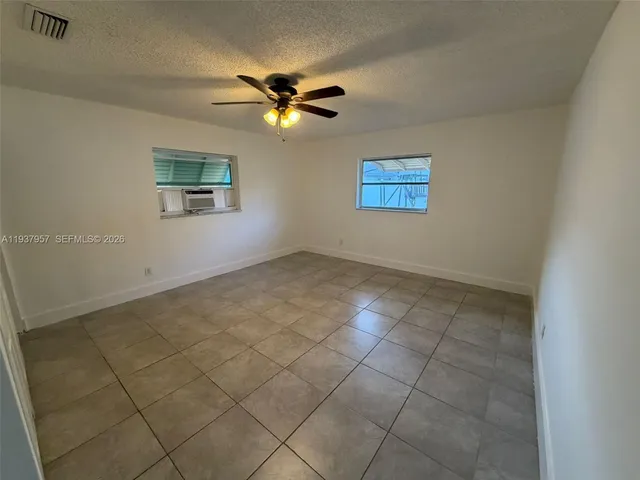 an empty room with a ceiling fan and glass door shower