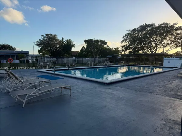 a view of swimming pool with seating space and trees in the background