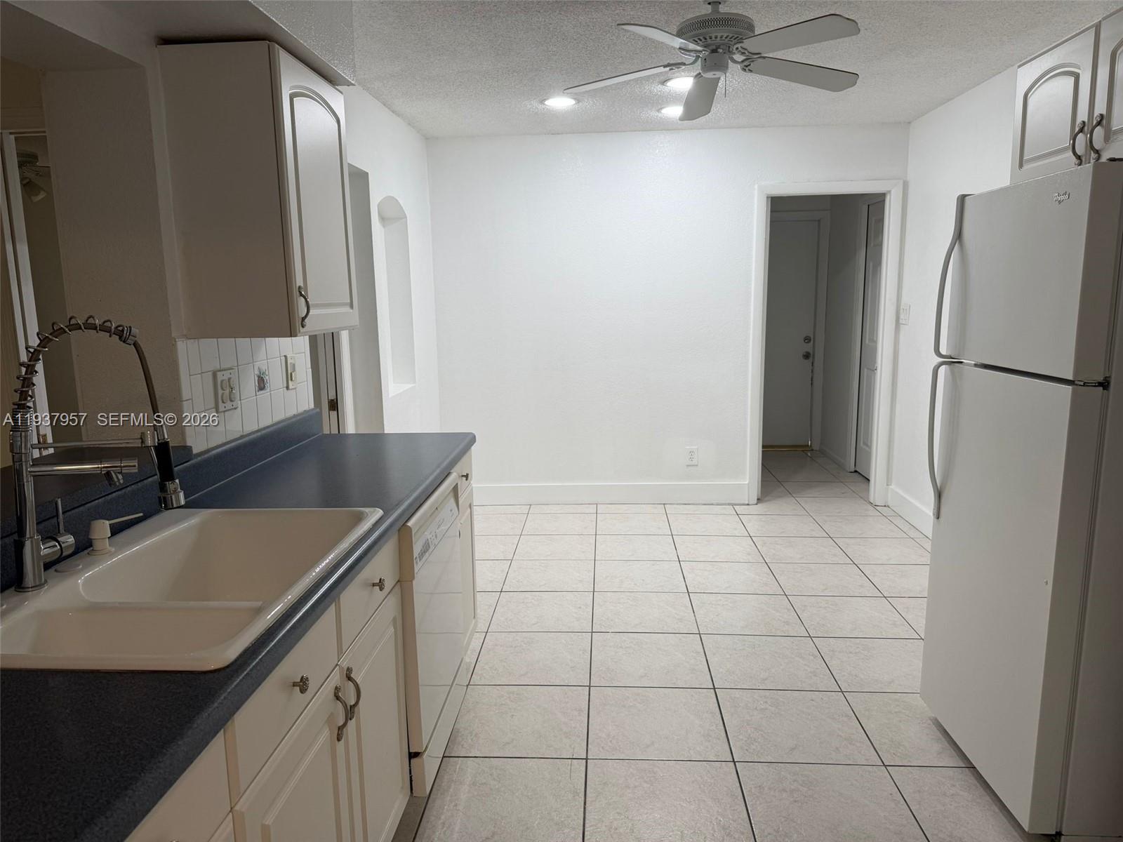 9507 Northwest 80th Court Tamarac, FL 33321 - Photo 6 of 22 a kitchen with a sink a refrigerator and cabinets