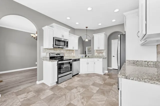 a kitchen with stainless steel appliances granite countertop a stove a sink and a refrigerator