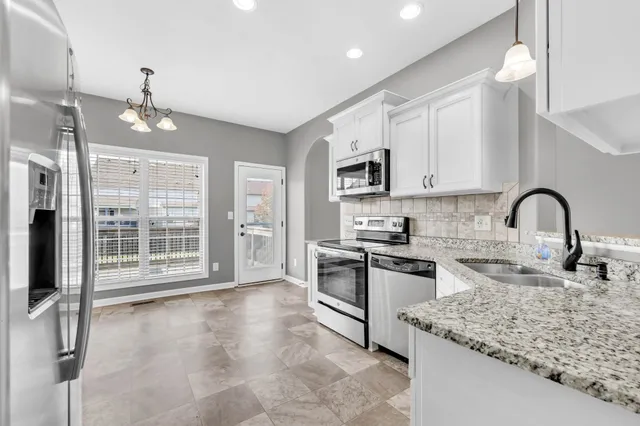 a kitchen with kitchen island granite countertop a stove top oven a sink a counter space and cabinets