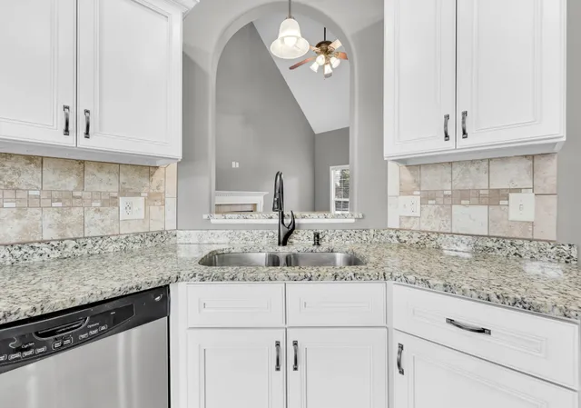 a kitchen with granite countertop white cabinets and a sink