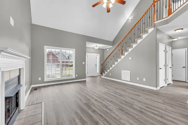 a view of an empty room with wooden floor and a fireplace