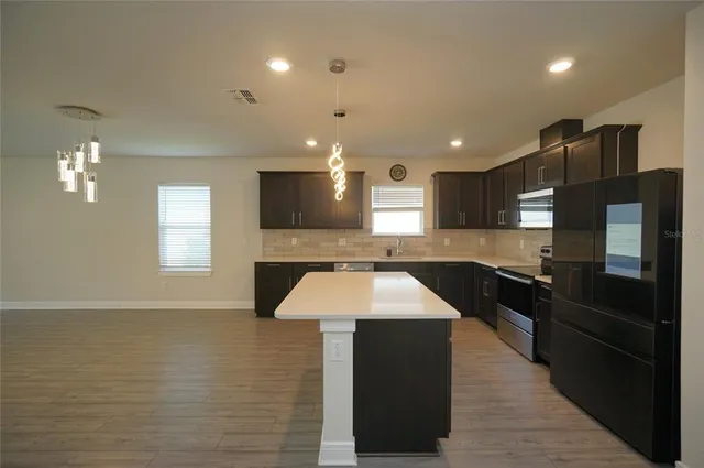 a large kitchen with stainless steel appliances kitchen island granite countertop a stove a sink and a refrigerator