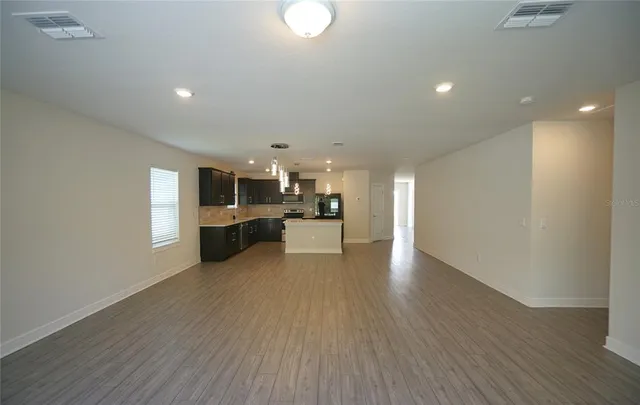 an empty room with wooden floor and chandelier